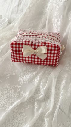 a red and white checkered box with a bow on it sitting on a bed