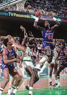 a group of men playing basketball in front of an audience at a sporting event, during the day