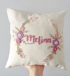 someone holding up a pillow with the word meluna embroidered on it in front of a white background