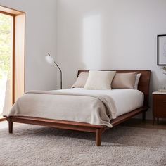 a bed sitting in a bedroom on top of a wooden floor next to a window