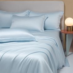 a bed with light blue sheets and pillows