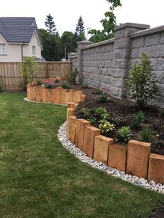 a garden area with grass, rocks and wooden planters on the side of it