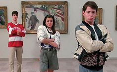 three people are standing in front of paintings and one is holding his arms crossed while the other looks at the camera