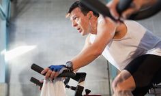 a man on a stationary bike in a gym doing exercises with an exercise trainer behind him