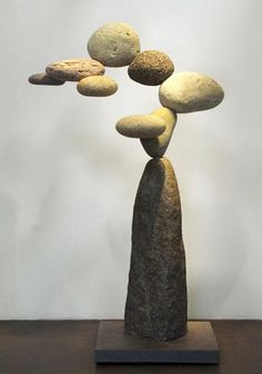 a sculpture made out of rocks sitting on top of a wooden table next to a white wall