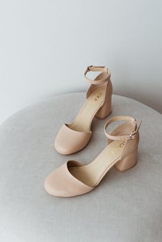 a pair of nude colored shoes sitting on top of a white table next to a wall