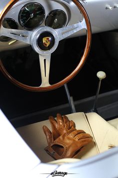 the interior of a classic car with brown leather gloves and gauges on the steering wheel