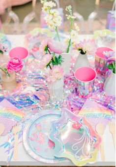 the table is set with pink and white flowers in vases, plates, and napkins