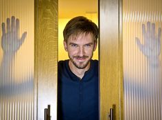 a man standing in front of two doors with his hands up to the door handle