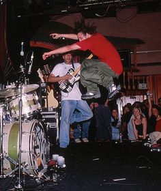 two men on stage playing musical instruments while people watch