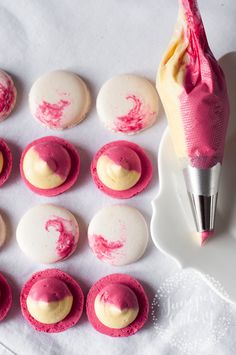 some pink and white cookies on a plate with a pen in the middle next to them