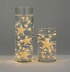 two clear glass vases with gold stars on them and one is filled with water