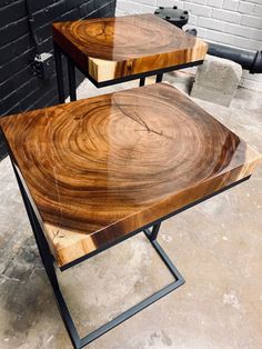 two wooden tables sitting on top of each other in front of a brick wall with black metal legs