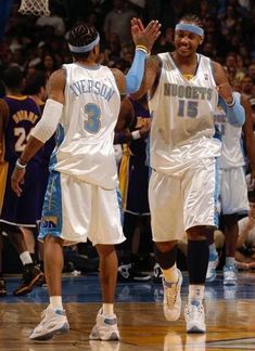 two basketball players walking on the court with their hands in the air and people watching