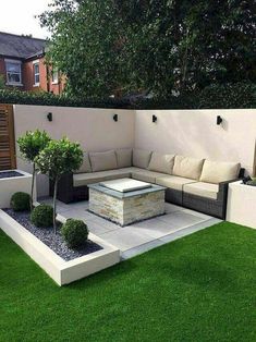 an outdoor living area with grass, couches and potted trees in the middle