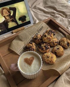 a tray with muffins and a cup of coffee next to an ipad on a bed