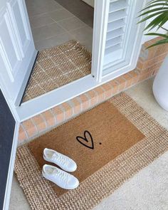 two pairs of white shoes sitting on the floor next to a door mat that says i love you