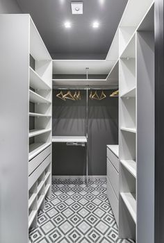 an empty walk in closet with white shelving and grey cabinets, lights on the ceiling