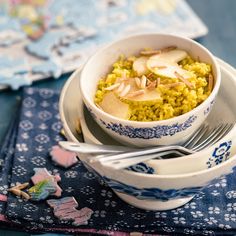 a bowl filled with food on top of a blue and white place mat next to a fork