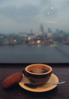 a cup of coffee on a saucer next to a cookie