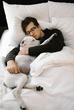 a man laying in bed with his dog