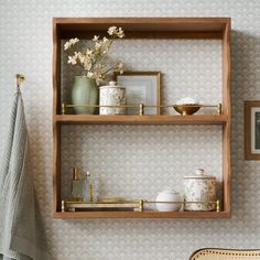 two wooden shelves with pictures, vases and other items on them in a bathroom