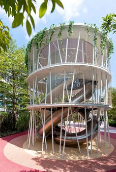 a large metal structure sitting on top of a lush green field next to a forest