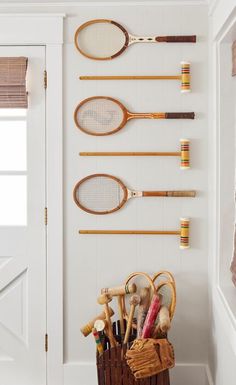 there are many tennis rackets hanging on the wall in this room, along with other sports related items