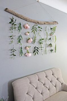 a couch sitting under a wooden branch with flowers hanging from it's sides on the wall
