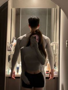 a man and woman taking a selfie in the mirror