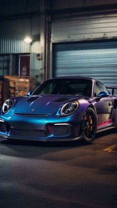 a purple and blue sports car parked in front of a garage door at night time