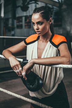 a woman in an orange and black top is holding a boxing glove