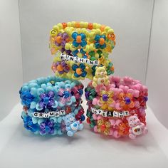 four bracelets with bear charms and words on them, all decorated in different colors