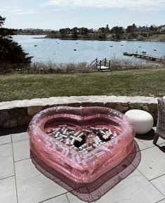 an inflatable heart shaped object sitting on top of a patio next to a lake