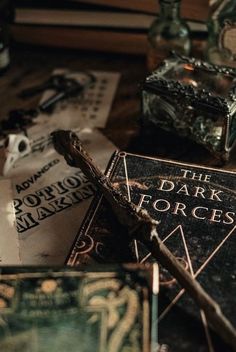 the dark forces book is laying on top of other books and glass bottles in front of it