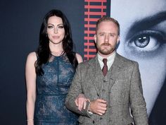 a man and woman standing next to each other in front of a large movie poster