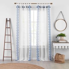 a window with sheer curtains and a ladder in front of it, next to a rug