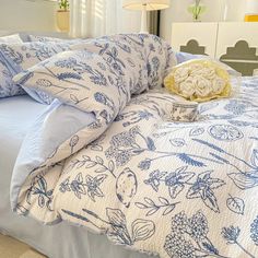 a bed with blue and white bedspread, pillows and flowers on it