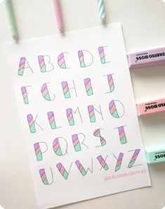 the letters and numbers are drawn on paper with colored pencils next to them,