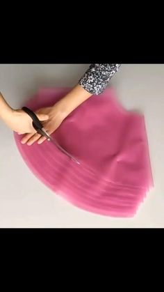a woman is cutting pink paper with scissors
