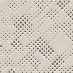 white perfored paper with holes and dots on it's surface, close up