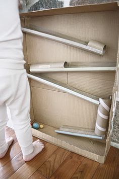 a person standing in front of an open box on the floor with toilet paper and other items