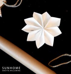 an origami flower sitting on top of a table next to some twine