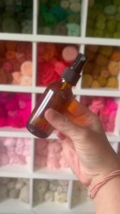 a person is holding a bottle in front of some shelves with different colors of beads