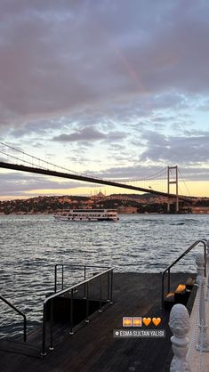 a bridge over water with boats on it and a rainbow in the sky at sunset