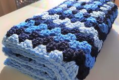 a blue and white crocheted blanket sitting on top of a table