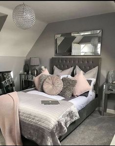 a bedroom with grey walls and pink pillows on the bed, along with two mirrors