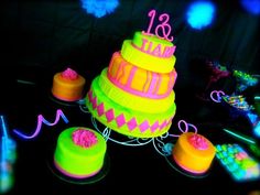 neon colored birthday cakes and decorations on a table