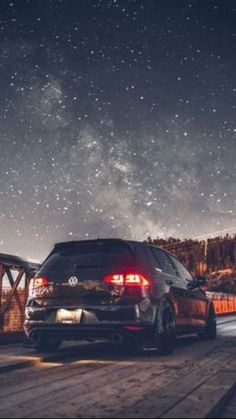 the back end of a car parked in front of a night sky filled with stars