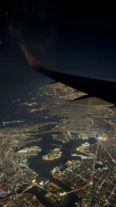 an airplane wing flying over a city at night